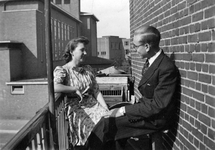 845177 Afbeelding van een man en vrouw op het balkon van het huis Amaliadwarsstraat 1, op de hoek met de Croesestraat ...